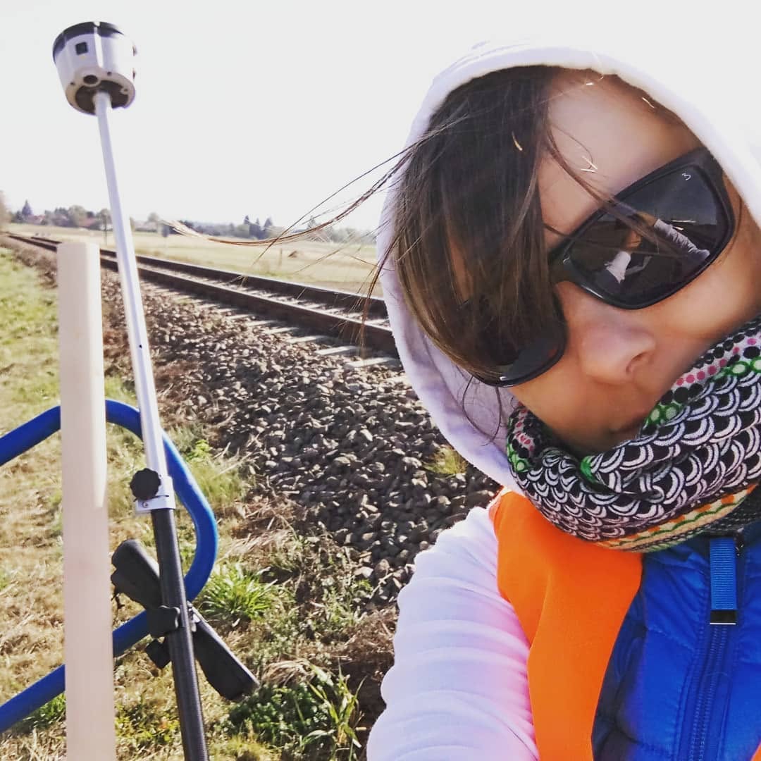 Geodeta z odbiornikiem GNSS podczas pomiarów przy torach kolejowych